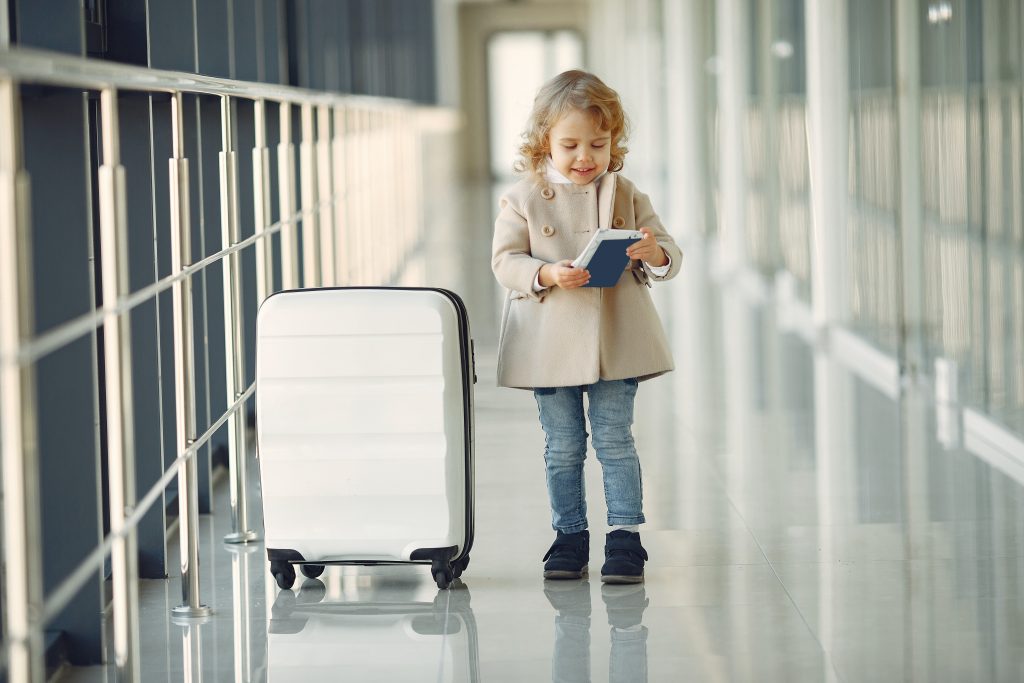 toddler girl with phone and suitcase at the airport