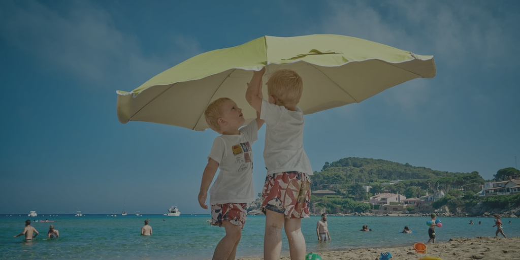 two toddlers putting up umbrella on the beach 
